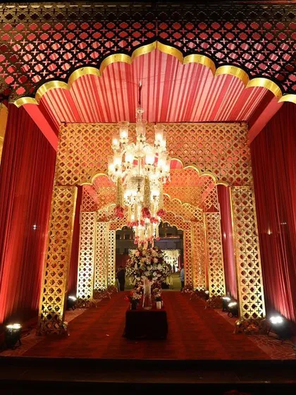I design grand, thematic entrances that transport guests into the world of the wedding. This royal Rajasthani-inspired entrance uses rich red fabrics, intricate gold patterns, and chandeliers to set a luxurious tone.