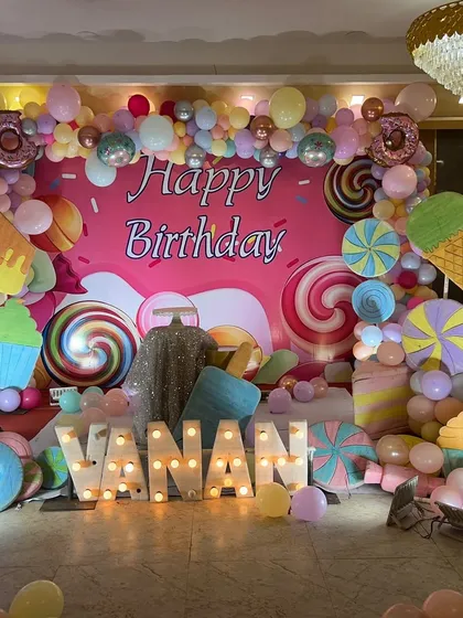We bring any birthday theme to life, like this vibrant Candyland party. The setup features a custom backdrop with giant lollipops and ice creams, a colorful balloon arch, and large marquee letters spelling out the name for a fun, immersive celebration.