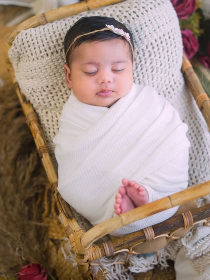 A peacefully sleeping newborn, perfectly wrapped in white. This classic pose in a rustic basket is a timeless way to remember their first days.
