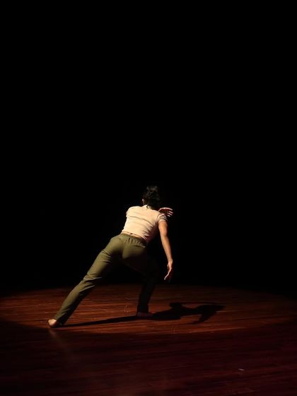 A dancer moves across the stage, her form silhouetted against the light.