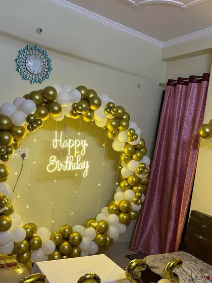 A gold and white circular balloon backdrop placed in a bedroom, creating an instant party atmosphere and a great spot for birthday photos.