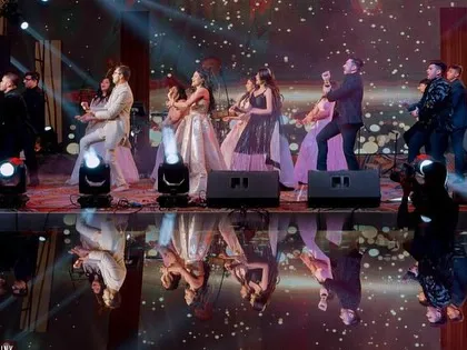 A high-energy family dance with the couple, perfectly reflected on the glossy stage floor.
