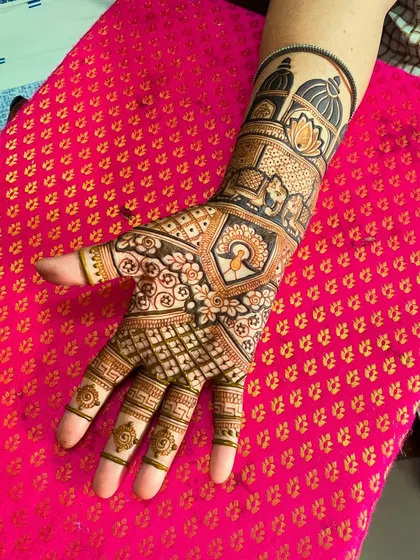 A close-up of a beautiful bridal mehendi. The design features a peacock, a lotus, and architectural domes, all intricately detailed.
