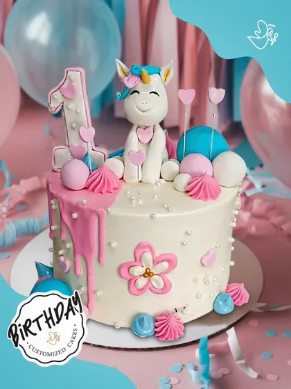 A sweet unicorn cake for a first birthday. Decorated with pink drips, flowers, and hearts, this cake is an adorable way to celebrate a very special milestone.