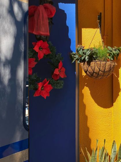 The strong contrast of a bright yellow wall and the deep blue shadow of a train decorated for Christmas.
