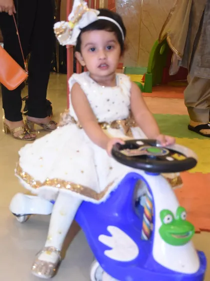 A happy toddler enjoying a ride on a colorful push car in the dedicated play zone. All my toys are clean, safe, and in great condition.