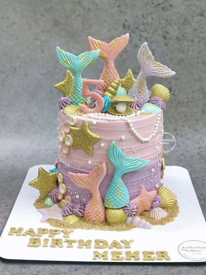 A magical mermaid cake with multi-colored tails and golden stars. The pink and purple ombre frosting adds to the enchanting look.