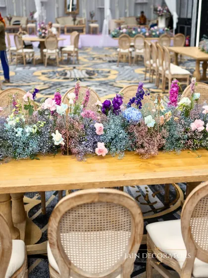 A long table adorned with a runner of colorful baby's breath. This simple yet stunning centerpiece adds a meadow-like, whimsical feel to the guest dining experience.