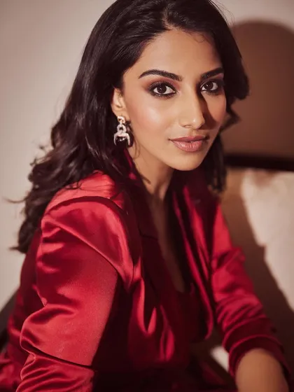 A close-up portrait in the red satin suit. The focus is on the model's confident expression and smoky eye makeup, which completes the glamorous evening look.