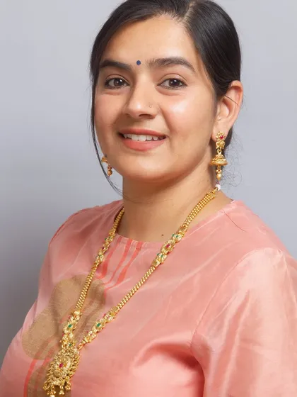 This traditional South Indian long necklace set features a beautiful pendant with intricate carvings and matching jhumka earrings. It is perfect for a classic temple jewellery look.