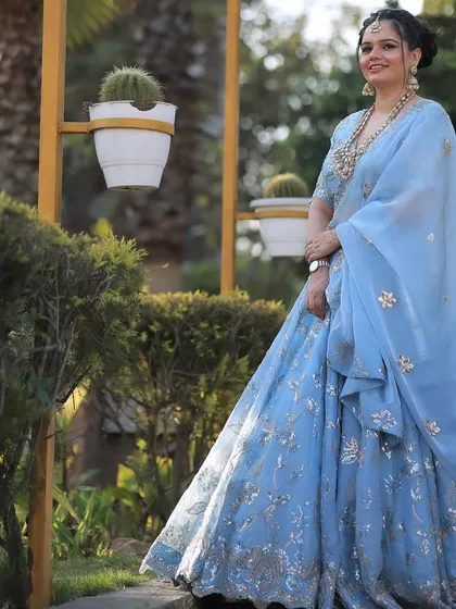 The full view of the beautiful blue lehenga. The braided updo and glowing makeup create a sophisticated and stylish look.