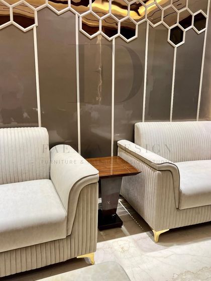 A sophisticated living room arrangement featuring a channel-tufted loveseat, blue high-back chairs, and a natural onyx marble coffee table. The mix of textures and forms creates a refined and elegant space.