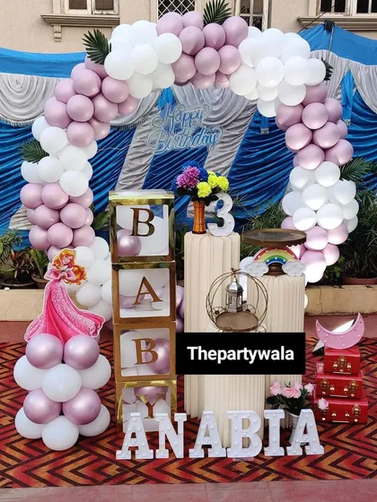 A cute princess theme with "BABY" blocks and a pink and white balloon arch. This setup is perfect for a smaller space or a more intimate first birthday party.