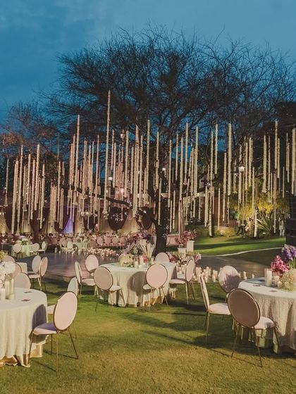 The guest seating area for the wedding, with lush green lawns and elegant round tables, designed for comfort and conversation.