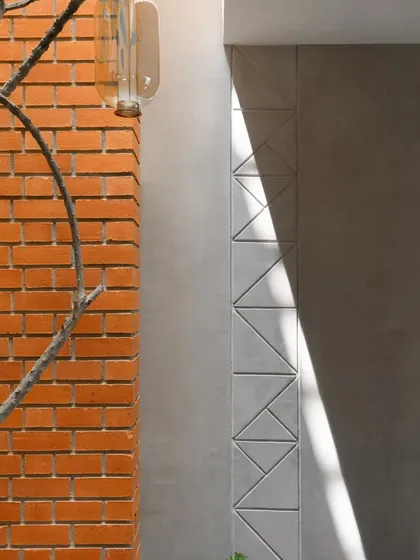 A close-up of the Phulkari-inspired motif etched into the concrete wall. This detail, catching the sunlight next to the exposed brick, is an example of how we weave cultural storytelling into the very fabric of the building.