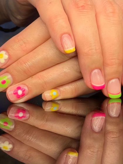 A vibrant and fun French manicure with multi-colored neon tips and hand-painted flowers.