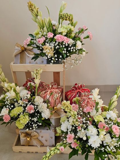 Here is a look at a full wedding hamper setup, with gifts beautifully arranged on tiered wooden crates. The abundance of fresh tuberoses, carnations, and baby's breath creates a feeling of pure celebration.