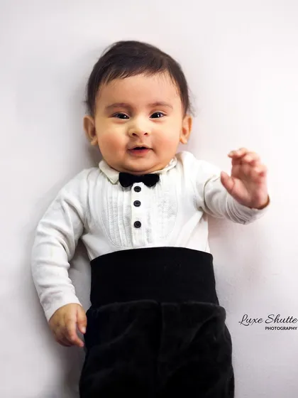 A little gentleman waves hello! This 5-month milestone portrait captures his budding personality in a sharp tuxedo-style outfit.