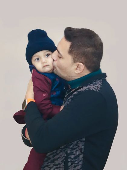 A tender moment between a father and his baby, as he gives his child a gentle kiss on the cheek.