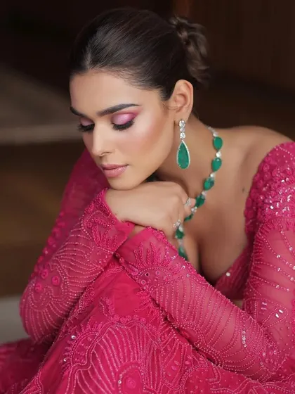 A close-up on the details, showing the intricate embroidery and the stunning emerald drop necklace.