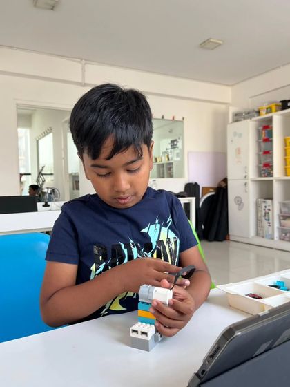 Concentration and creativity go hand-in-hand at our workshops. This young builder is assembling a small robot, learning about mechanics and engineering principles in a tangible way.
