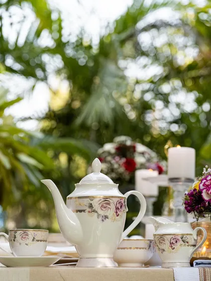 An elegant tea set from Vigneto, photographed in a lush garden setting. The composition balances the delicate porcelain with the vibrant natural background, creating a perfect afternoon tea scene.