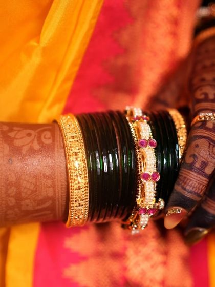 A detailed shot of the rich henna stain on the bride's arm, peeking out from behind her bangles. The color is deep, even, and absolutely beautiful.