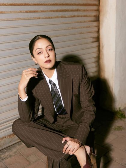 A seated pose that exudes relaxed confidence, showcasing the wide-leg trousers and sharp tailoring.