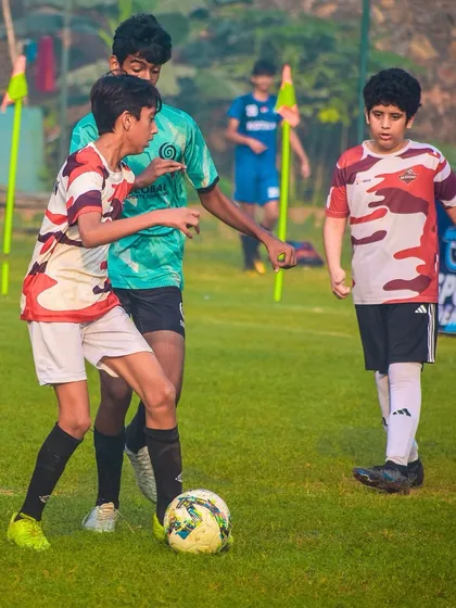 Players from two teams are in a tight contest for the ball, a great example of competitive youth football.