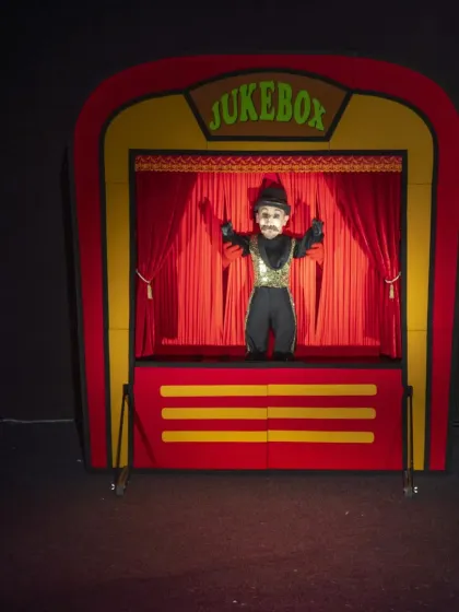 A mustachioed, sequined puppet strikes a pose in the 'Jukebox' show. The performance is a visual and musical treat, reinventing well-known songs.