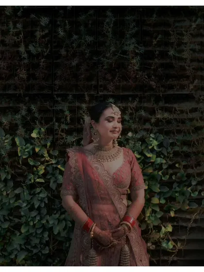 A serene portrait of the bride, Gurveen, against a wall of green ivy, her eyes closed, enjoying a moment of peace.
