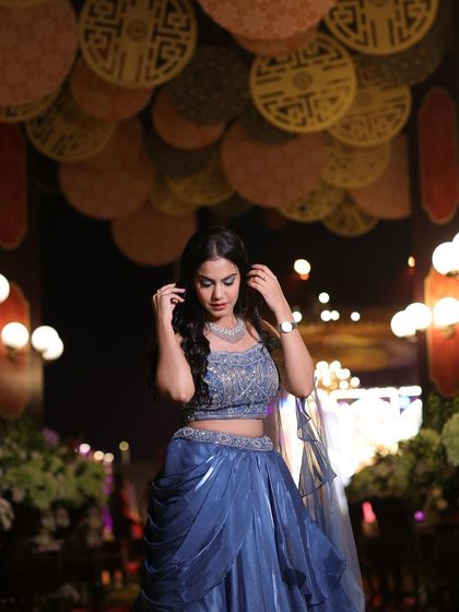 A shot from a sangeet event, showing how this blue gown looks in a festive, decorated environment.