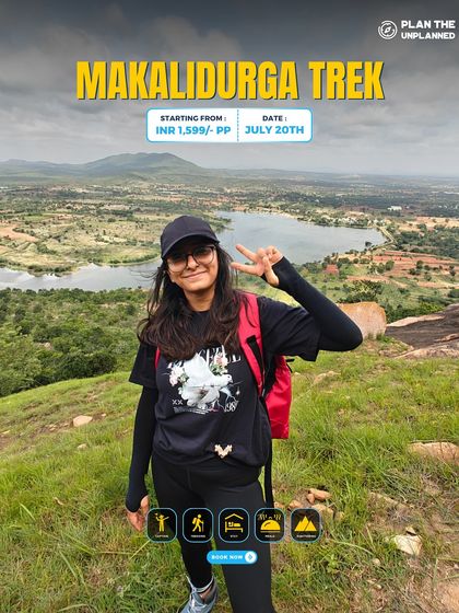 A trekker smiles for the camera on the Makalidurga trek, with a lake visible in the background.
