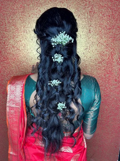 The hairstyle for this look features soft curls adorned with baby's breath, creating a romantic and delicate effect.