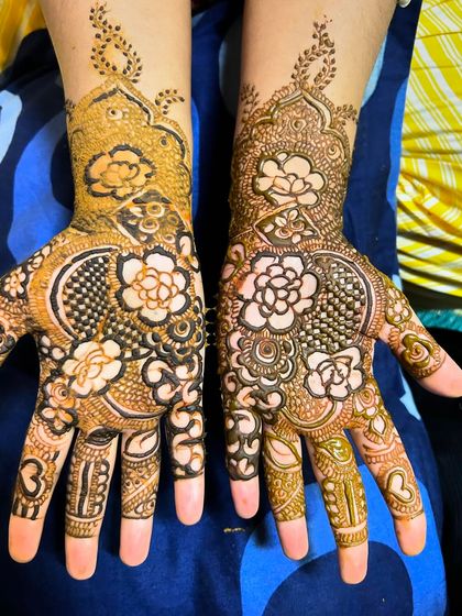 An intricate Pakistani henna design with delicate, reverse-fill floral patterns. The use of negative space makes the flowers pop, creating a unique and eye-catching effect.