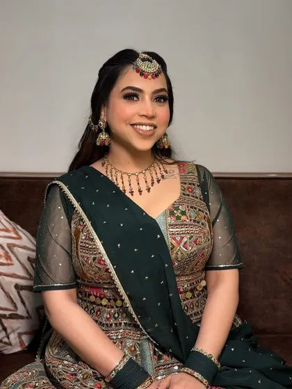 A full view of her festive outfit. The makeup is designed to complement the intricate embroidery and colors of her dress.