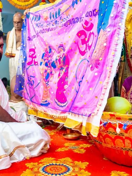A moment from a Telugu wedding ceremony, showing the 'jeelakarra bellam' ritual where a cloth separates the bride and groom.