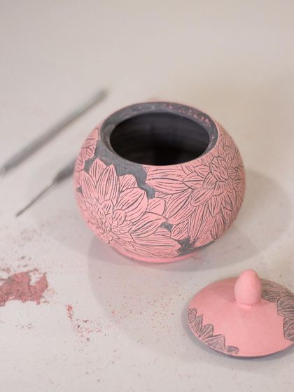 A close-up of a finished sgraffito jar. The contrast between the pink underglaze and the dark clay creates a stunning visual effect. You can make this too!