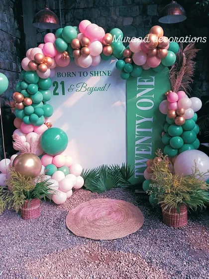 A lovely pastel-themed backdrop for a 21st birthday. The sign reads 'Born to Shine, 21 & Beyond', framed by a balloon arch in mint green, pink, and gold, with tropical plant accents.