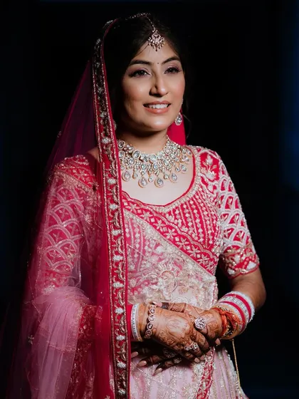 A fantastic fusion of classic and modern. Mamta's bridal look featured a stunning pink and red lehenga with diamond jewelry, paired with soft, glowing makeup. ❤️