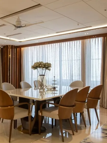 The elegant dining area, with modern chairs and a marble-topped table, is perfectly positioned to enjoy both family meals and the city view.