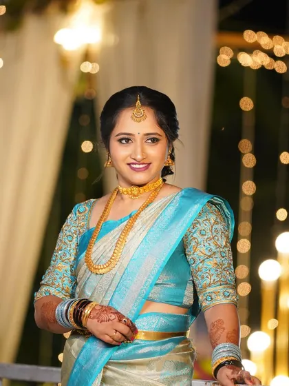 A portrait showcasing the elegant blue saree and gold jewellery.