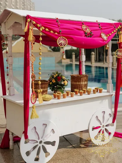 A charming chai and snack cart, decorated with rani pink drapes and traditional hangings. This is a great way to enhance the guest experience with themed food stations.