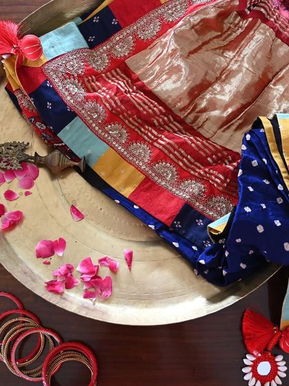 Preparing the saree for its new home. The rich colors of the patchwork, the shimmer of the Zardozi, and the deep blue of the Bandhni silk are laid out, ready to be worn and cherished.