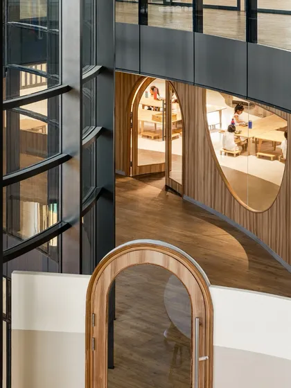 An overhead view at Vedanya School showing the interplay of curved balconies, glass elevators, and arched doorways. The fluid forms create a landscape of discovery that is open, playful, and always in motion.
