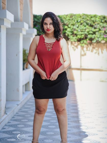 A strong, full-length standing pose in an outdoor corridor. The repeating arches create a beautiful sense of rhythm and depth in the composition.