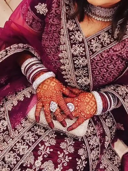 The deep color of the henna stain looks elegant against the bride's ornate purple outfit and jewelry.