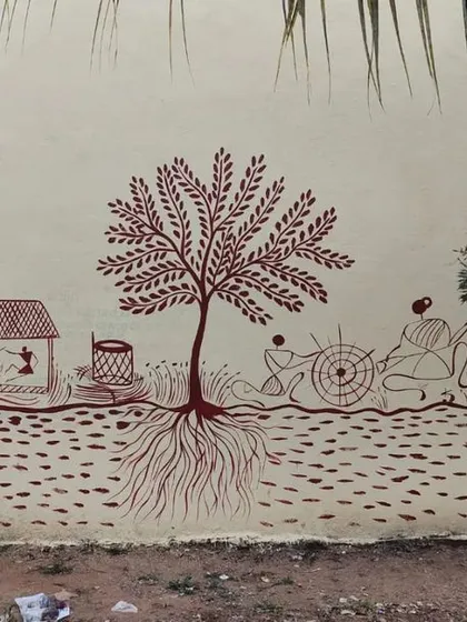 An example of a custom color palette for a Warli mural. Here, I used earthy red-brown paint on a light-colored wall to create a different feel, showing a scene of village life centered around a large tree with intricate roots.