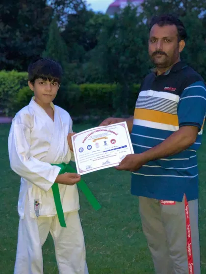 Another student proudly displays his green belt certificate. Progress is marked by these important milestones.