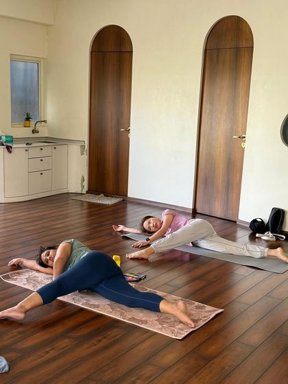 Students resting in a gentle supine twist. This pose is a perfect way to unwind the spine and release tension after a dynamic practice.